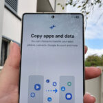 a smartphone held in a hand with a prompt to copy apps and data scaled