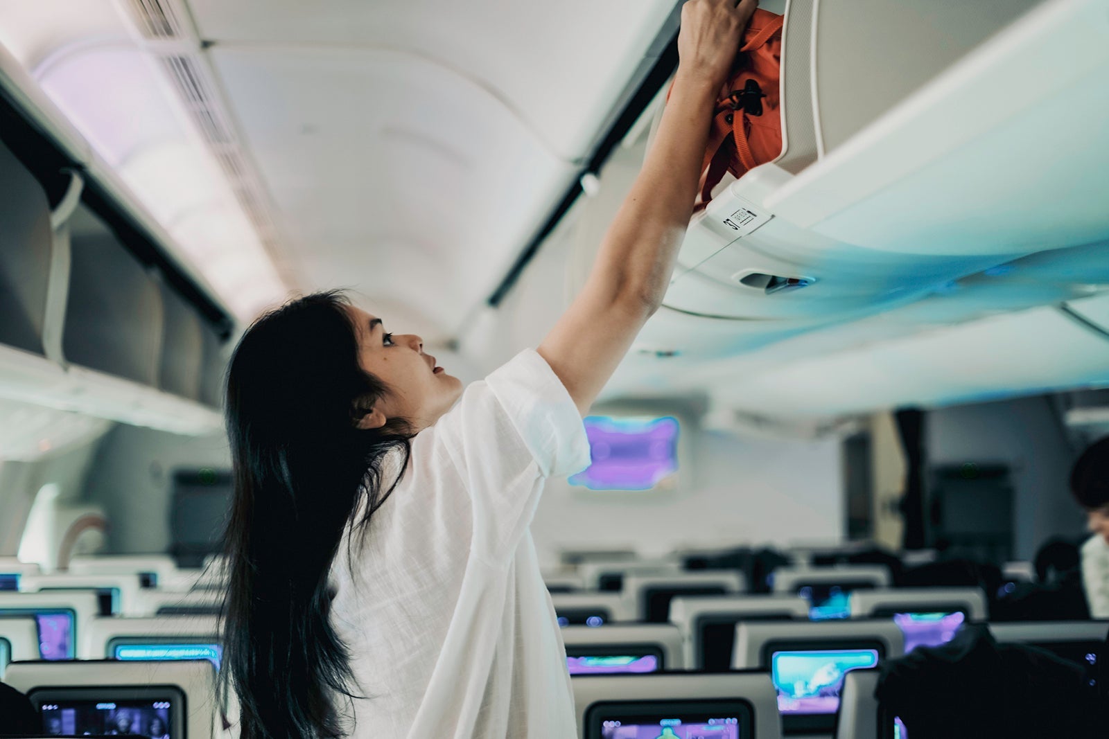 Passanger trying to get bag out of luggage overhead on airplane rudi suardi