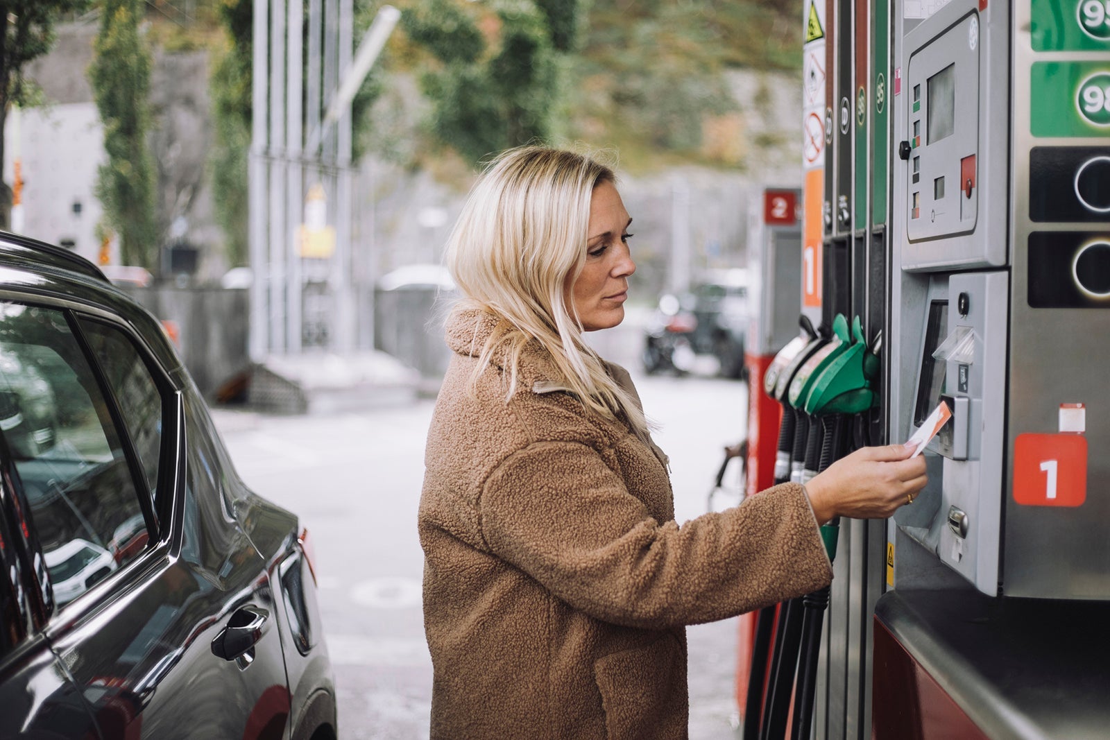 Woman paying for gas with contactless credit car payment at gas station Maskot