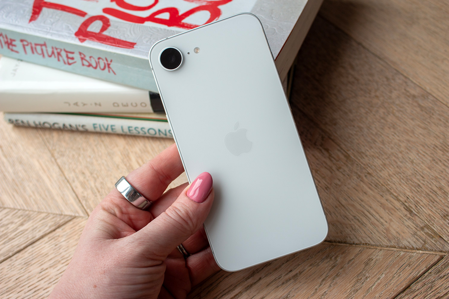 Apple iPhone 16e in hand rear