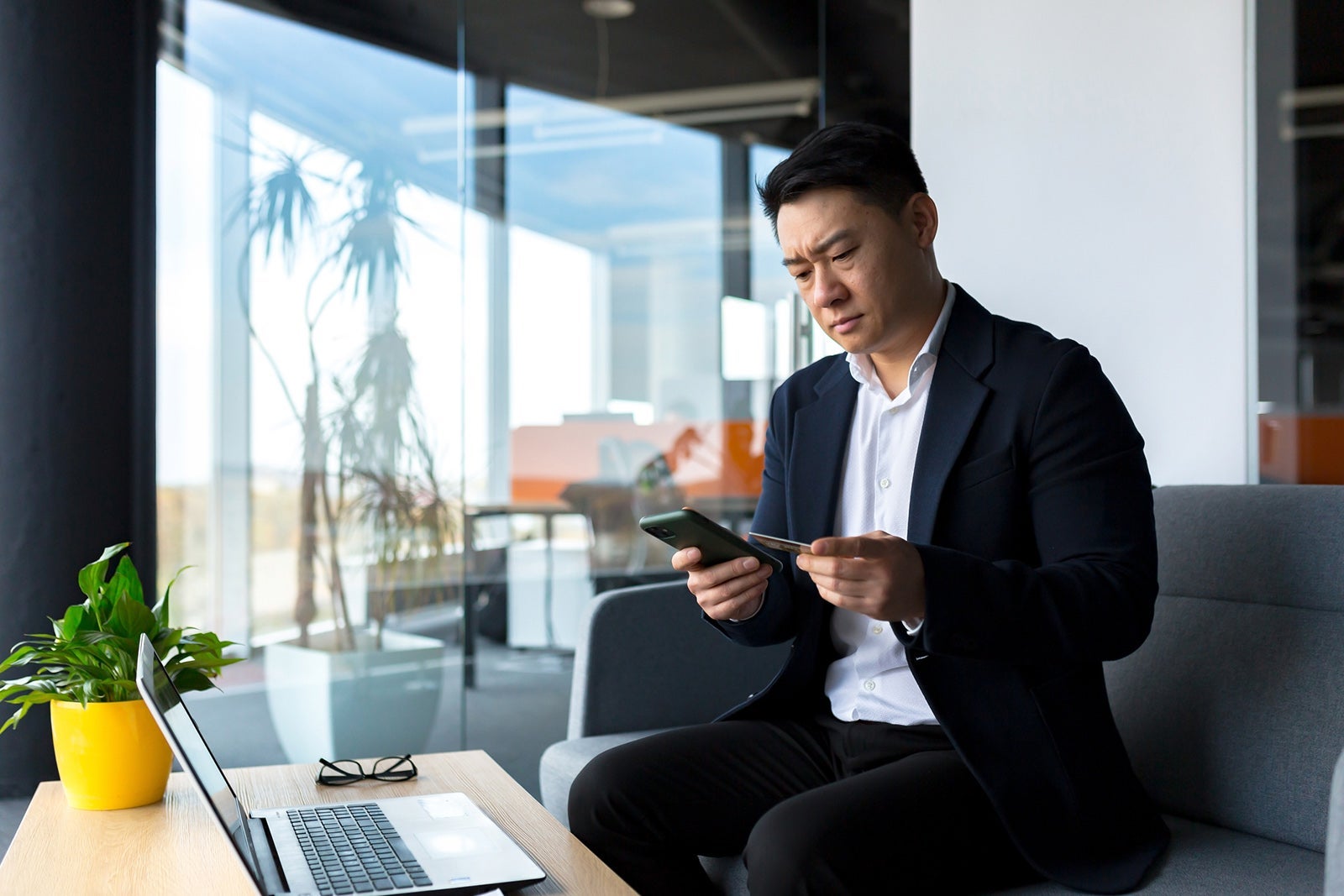 Confused and frustrated man looking at credit card charges on smart phone Liubomyr Vorona