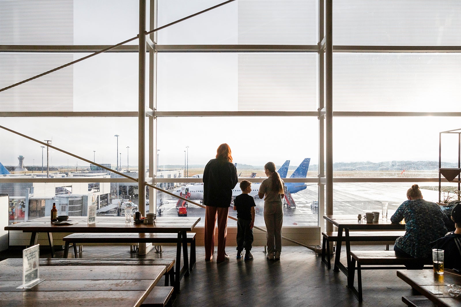 Family looking out window at airplanes in terminal SolStock