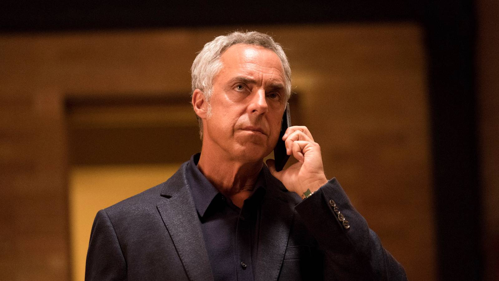 harry bosch looks serious while talking on the phone in bosch season 3