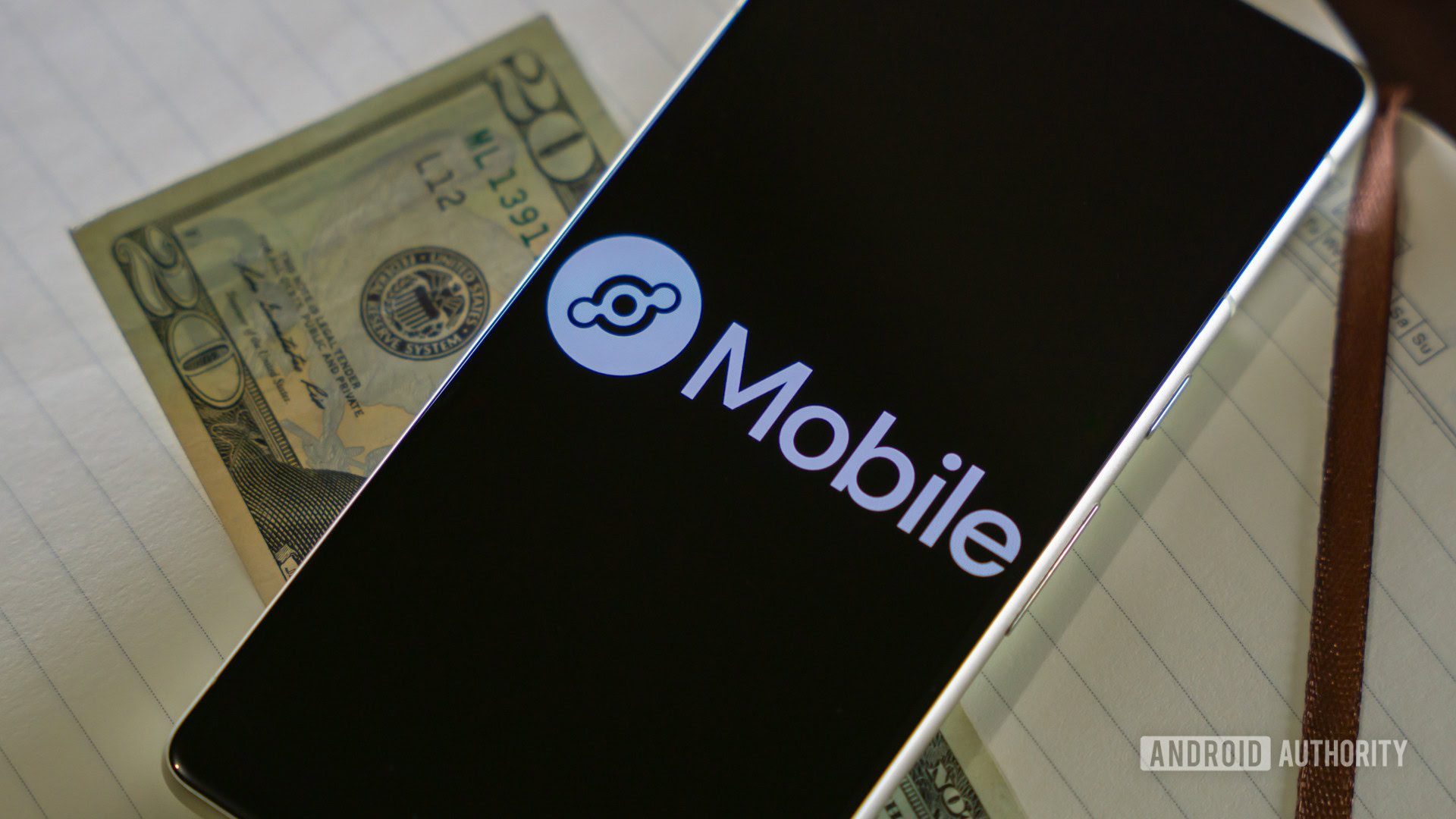 Helium Mobile logo on smartphone next to 20 bill 2