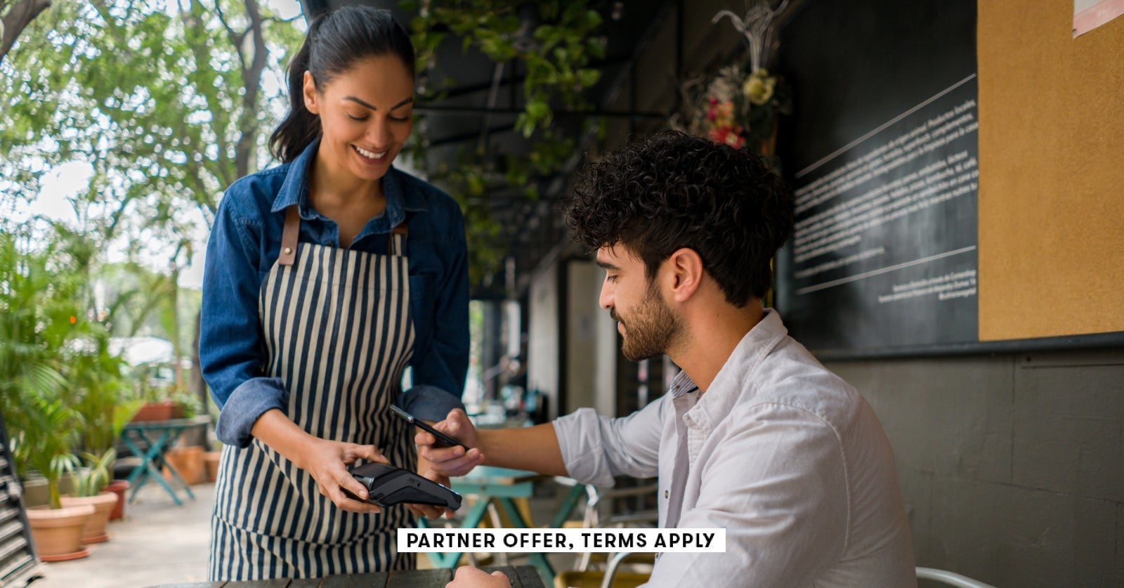 SOCIAL IMAGE PARTNER OFFER TERMS APPLY Man making a contacless payment at a restaurant using his cel