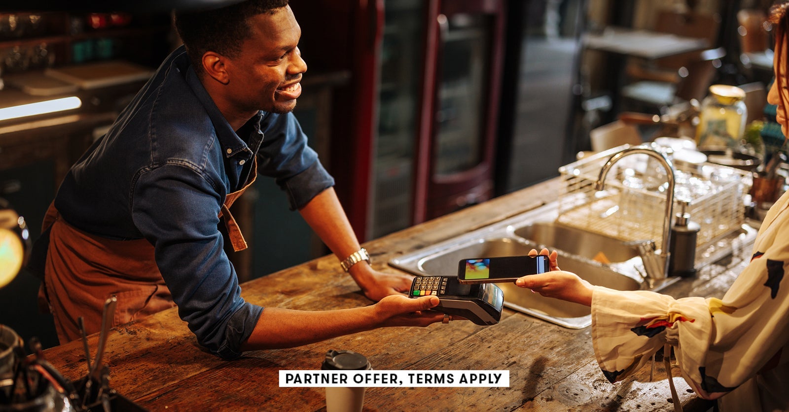 SOCIAL IMAGE PARTNER OFFERS TERMS APPLY Bartender holding contactless payment terminal for person to